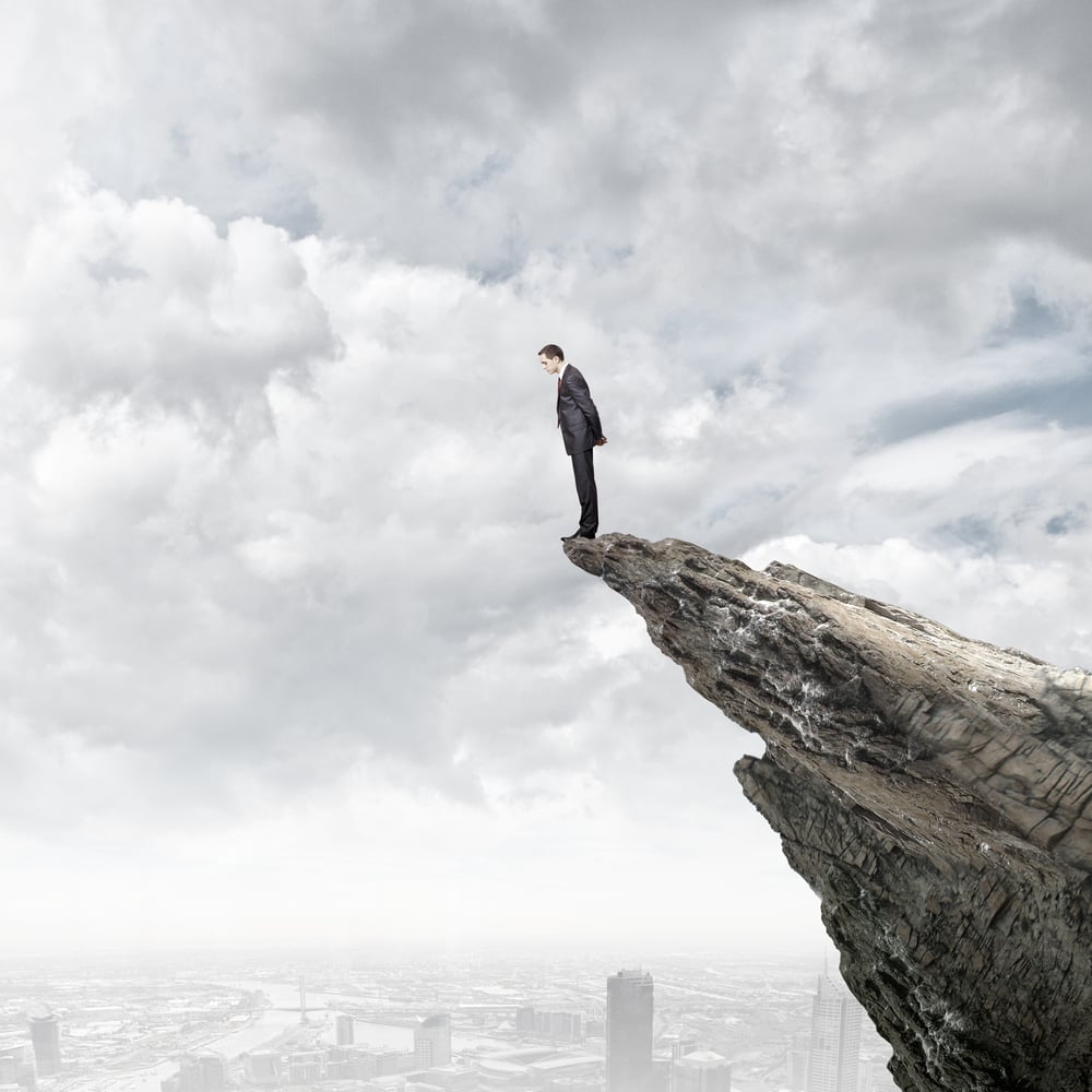 Businessman standing on edge of hill and looking down